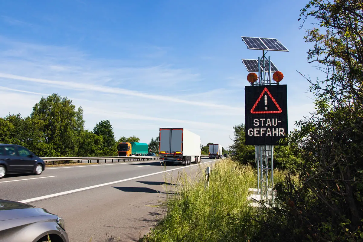Mobile LED-Stauwarnanlage von IBOMADE mit der Anzeige „Stau-Gefahr“ am Fahrbahnrand der A1 zwischen Lohne und Bramsche