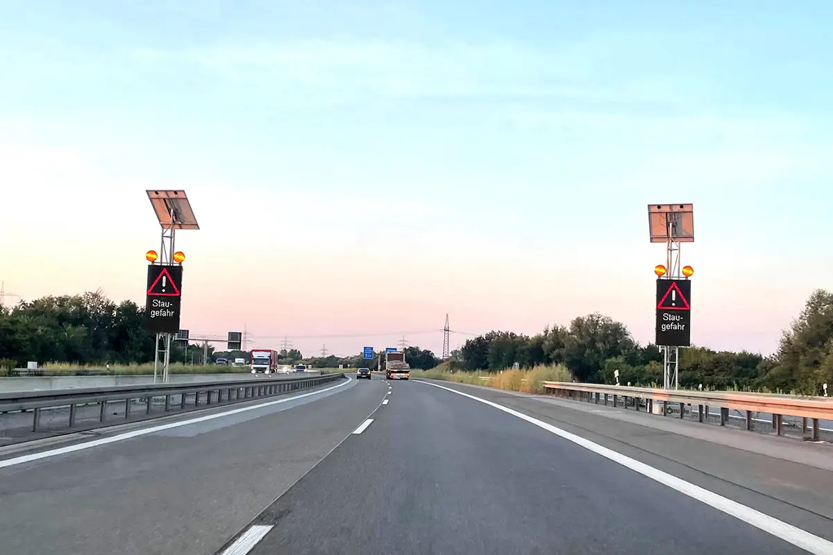 Zwei LED-Stauwarnanlagen mit der Anzeige „Staugefahr“ beidseitig der A6 bei Schwetzingen in der Abenddämmerung