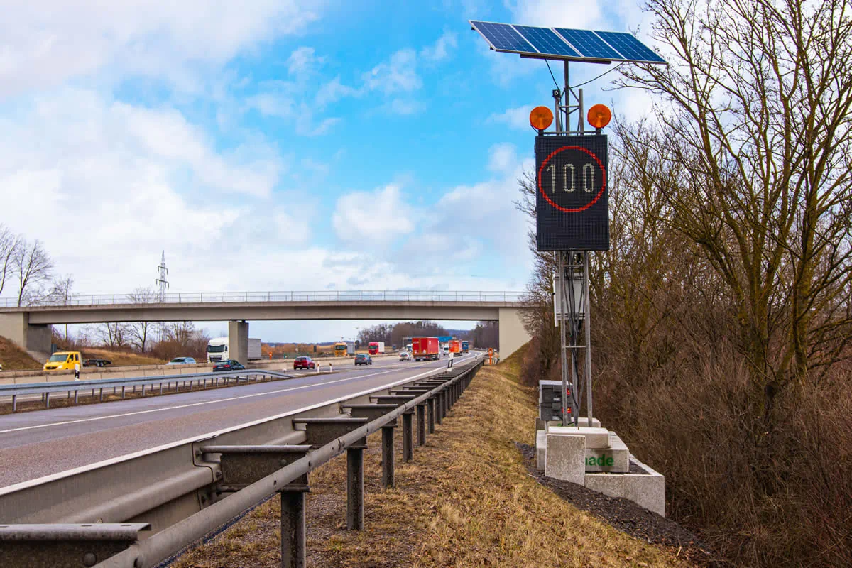 Nahaufnahme einer LED-Stauwarnanlage mit Solarmodul, gelben Warnleuchten und Tempo-100-Anzeige an der A81