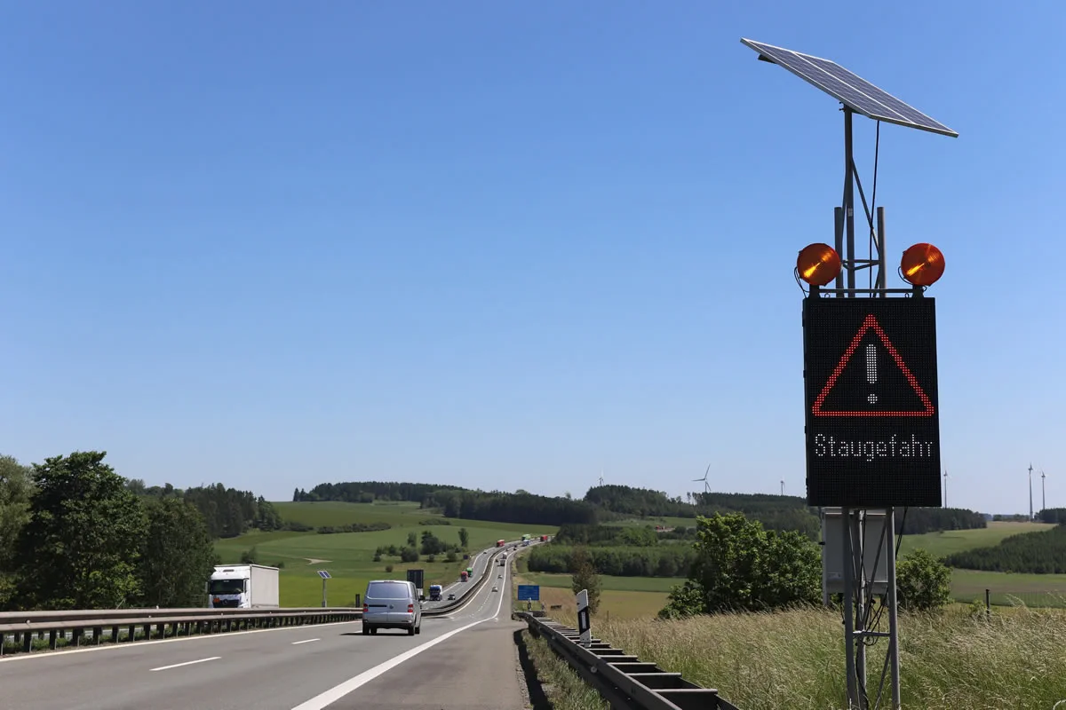 Nahaufnahme einer mobilen LED-Stauwarnanlage mit Solarmodul und der Anzeige „Staugefahr“ an der A93